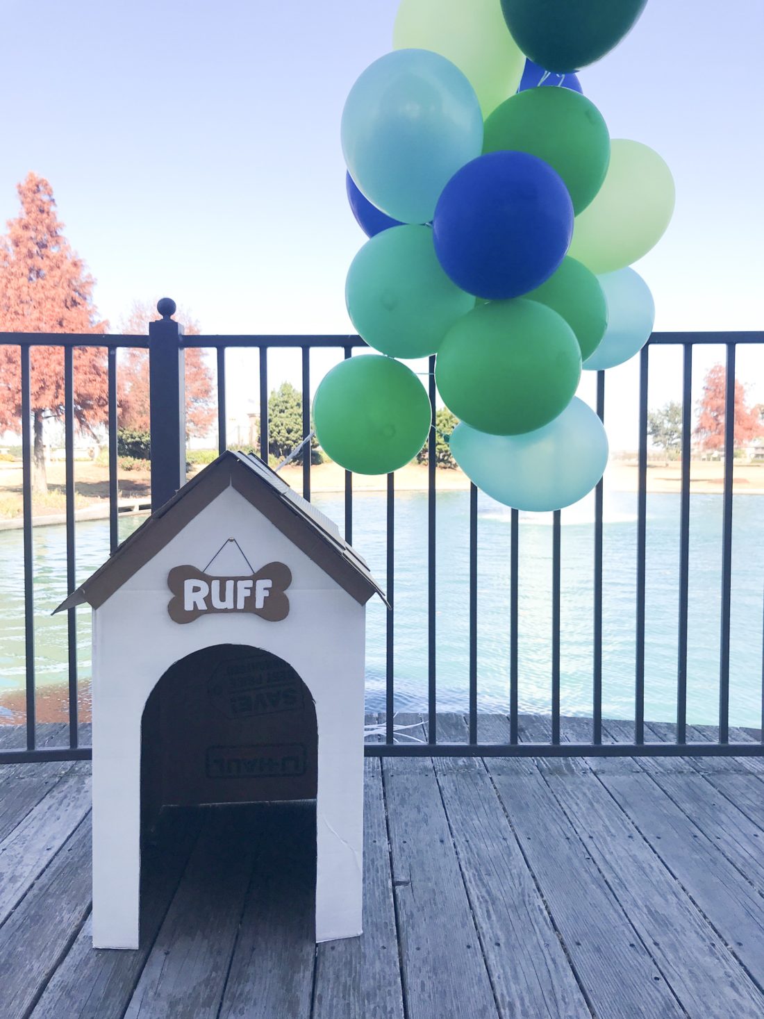 cardboard dog house, dog themed birthday party decor, blue and green balloons 